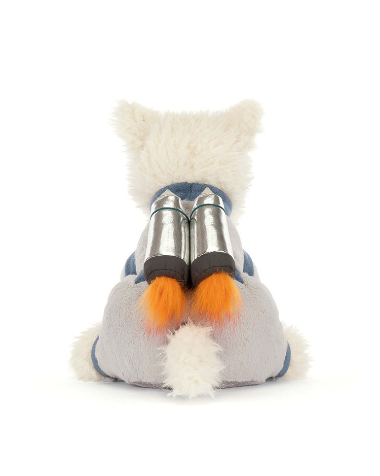 A Jellycat plush depicting a white animal with pointy ears and an orange-tipped tail, seen from behind in the blue "munro scottie dog space outfit" with two silver rocket boosters on its back.