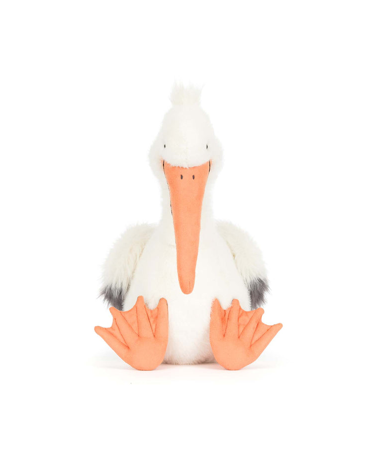 The Jellycat Keli Pelican plush toy features a white body, fluffy wings with black tips, an orange beak, and large webbed feet, shown sitting upright against a white background.