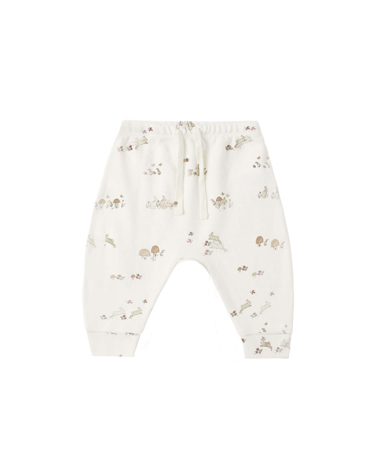 The drawstring pant in bunnies by quincy mae features white organic cotton with a pull-on style, an elastic waistband and drawstring waist, and is adorned with a subtle print of small bunnies, animals, and plants in soft brown and beige tones.