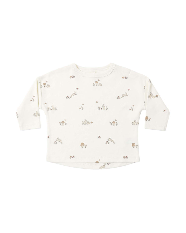 Introducing the "long sleeve tee in bunnies" by quincy mae—a long-sleeved white baby shirt made from soft organic cotton, featuring an all-over print of delicate bunnies and nature-inspired designs in subtle light brown and beige hues. This round-neck tee is the perfect way to add gentle charm to your little one’s wardrobe.