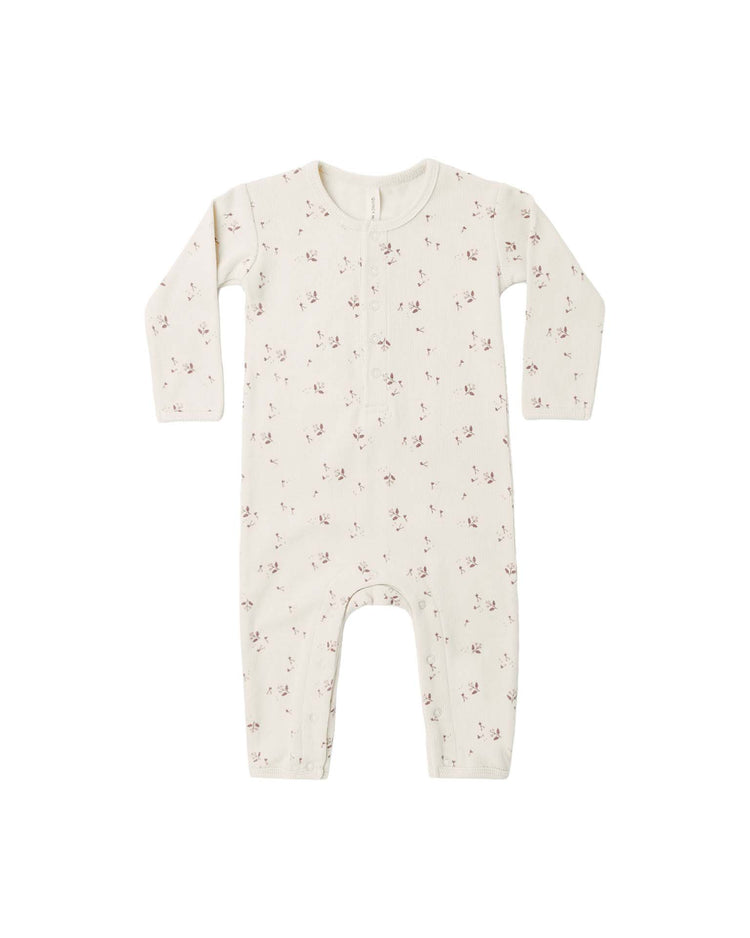 The "ribbed baby jumpsuit in fall ditsy" by quincy mae is a cream-colored, long-sleeve organic cotton jumpsuit with a slim-fit rib knit design, adorned with a small pink floral fall ditsy print. It features front buttons and convenient leg snaps, shown on a white background.