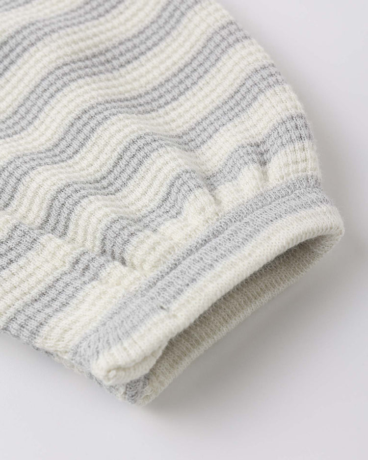Close-up of the quincy mae waffle jumpsuit in sky stripe, showing a ribbed sleeve knit from organic cotton with cuffed end. Wavy grey and off-white stripes highlight the visible texture and stitching.