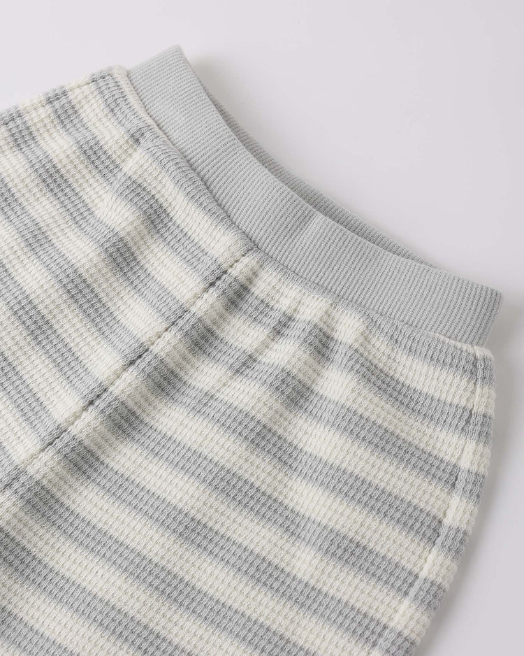 A close-up of the quincy mae waffle sweater set in sky stripe, showing soft ribbed lounge pants with horizontal light gray and off-white stripes and a light gray elastic waistband, laid flat on a white background.