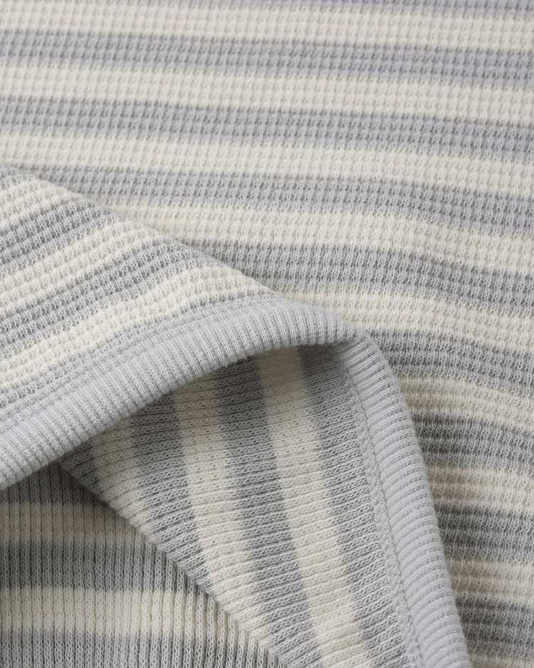 A close-up of the quincy mae waffle sweater set in sky stripe shows soft, ribbed organic cotton with horizontal grey and off-white stripes—perfect for cozy loungewear. One corner is folded to reveal the texture on both sides.