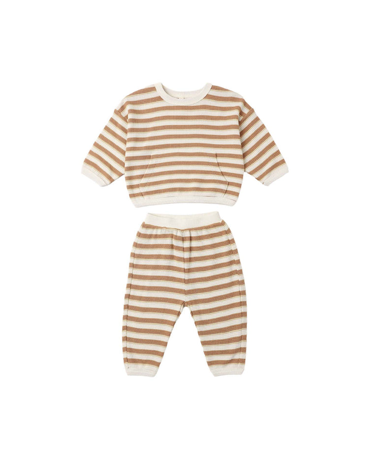 The quincy mae waffle slouch set in spice stripe is a two-piece children’s outfit featuring beige and white horizontal stripes. Crafted from soft organic cotton, it includes a long-sleeve top and matching pants—both finished with white cuffs and waistband. Displayed on a plain white background, this cozy set offers comfort and timeless style for little ones.