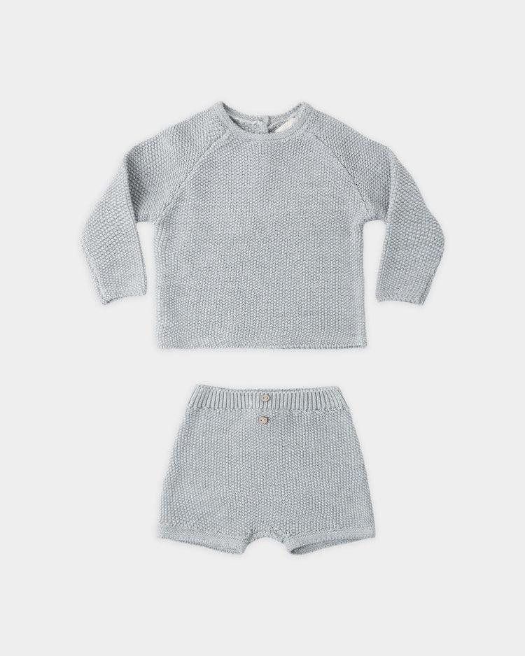 The summer knit set in heathered sky by quincy mae features a light grey organic cotton sweater with a textured pattern and matching shorts with a button waist, both shown laid flat on a white background.