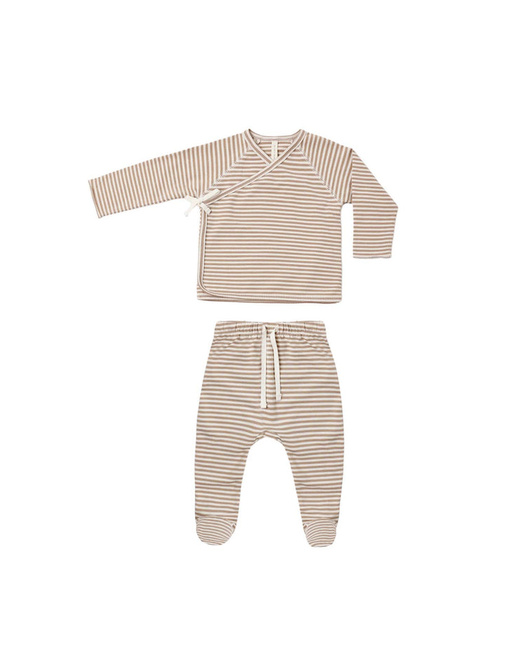The quincy mae wrap top + footed pant set in almond stripe is a long-sleeve organic cotton baby outfit, featuring a beige and white horizontal stripe pattern. The set includes a wrap-style top and matching footed pants with a drawstring, perfect as a newborn coming home outfit. It is displayed on a white background.