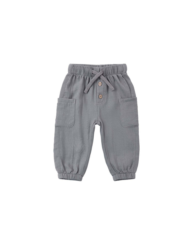 The luca pant in slate by quincy mae features an elastic waistband with a drawstring, two buttons, and large side pockets. These comfortable woven baby pants have elastic cuffs at the ankles and are shown on a plain white background.