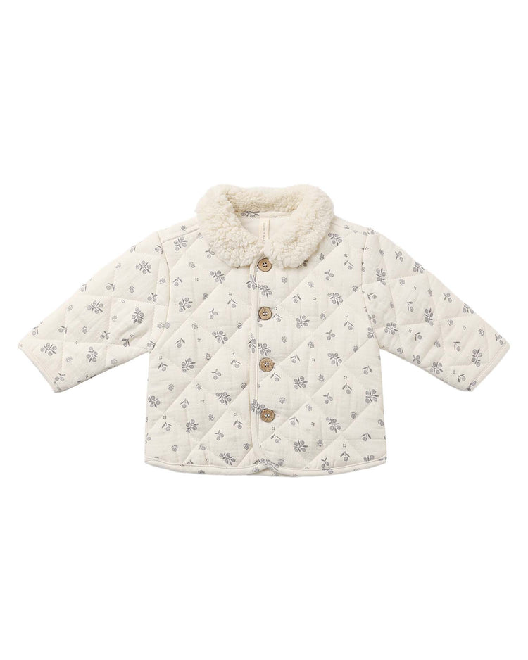 The "quilted jacket in winter berry" by quincy mae is crafted from organic cotton and features a cozy quilted design with long sleeves, a fluffy collar, wooden buttons, and a subtle gray floral print. Its soft texture makes it perfect for keeping your baby warm in cool weather.