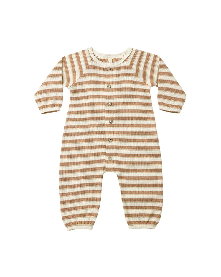 The quincy mae waffle long sleeve jumpsuit in spice stripe, featuring horizontal brown and cream stripes, a front coconut button closure, and elastic cuffs at the wrists and ankles, is laid flat on a white background.