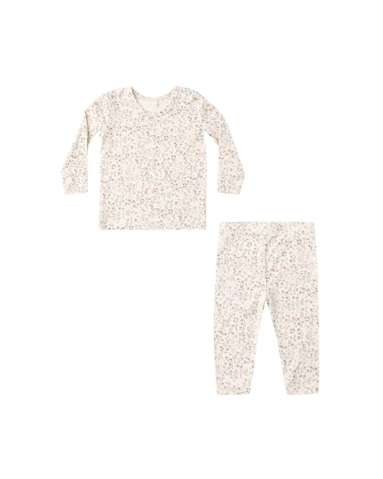 The quincy mae bamboo pajama set in bloom is a two-piece children’s sleepwear ensemble, featuring long sleeves and pants in a light color with a subtle, delicate floral print pattern. The set is shown against a white background.