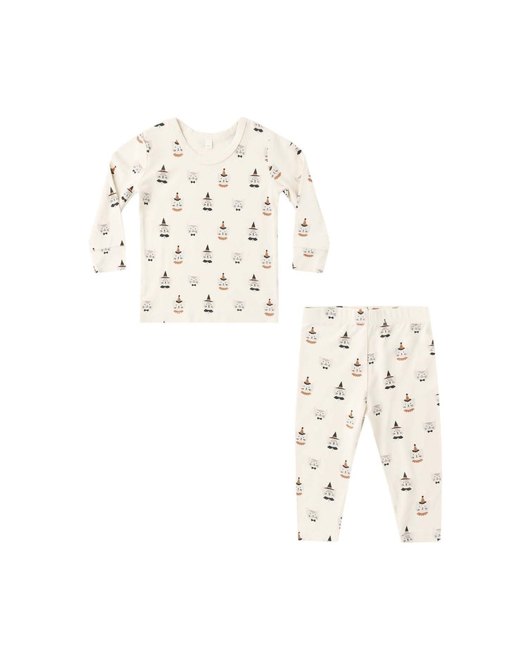 A two-piece children’s bamboo pajama set by quincy mae, featuring a slim-fit long sleeve top and pants, both white with a playful costume kittens print, laid flat on a white background.