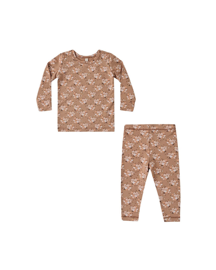 The quincy mae bamboo pajama set in fall floral is a two-piece slim-fit outfit for kids, featuring a long sleeve top and leggings in light brown with a delicate white and pink floral print. The set is displayed laid flat on a white background.