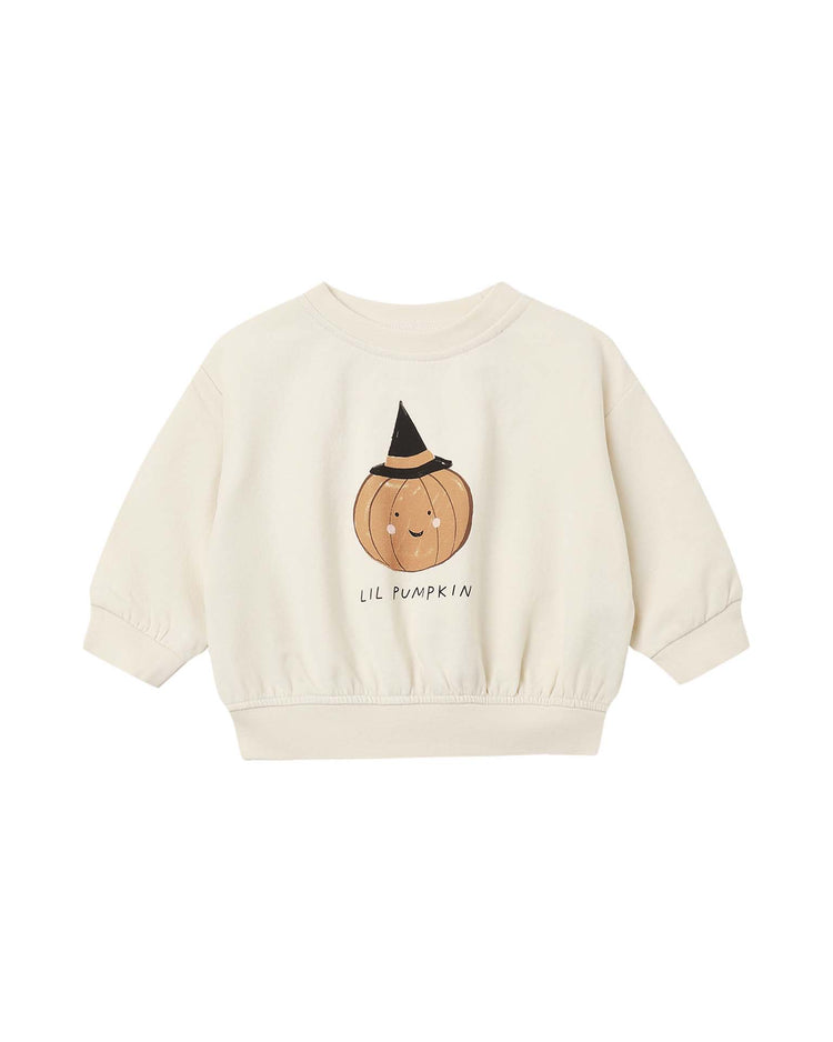 Introducing the relaxed fleece sweatshirt in lil pumpkin by Quincy Mae—a cream-colored organic cotton sweatshirt for kids, featuring a smiling pumpkin in a witch hat and “Lil Pumpkin” printed underneath. This cozy essential combines style and comfort, perfect for little ones.