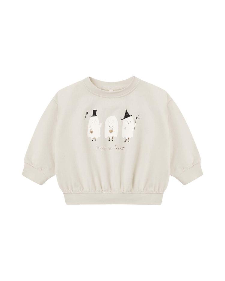 The “relaxed fleece sweatshirt in trick or treat” by quincy mae is a cream-colored organic cotton sweatshirt for children, featuring three adorable ghost illustrations each sporting a different hat, and a playful “trick or treat” print beneath. Gathered elastic at the sleeves and waist provides a cozy, comfy fit.