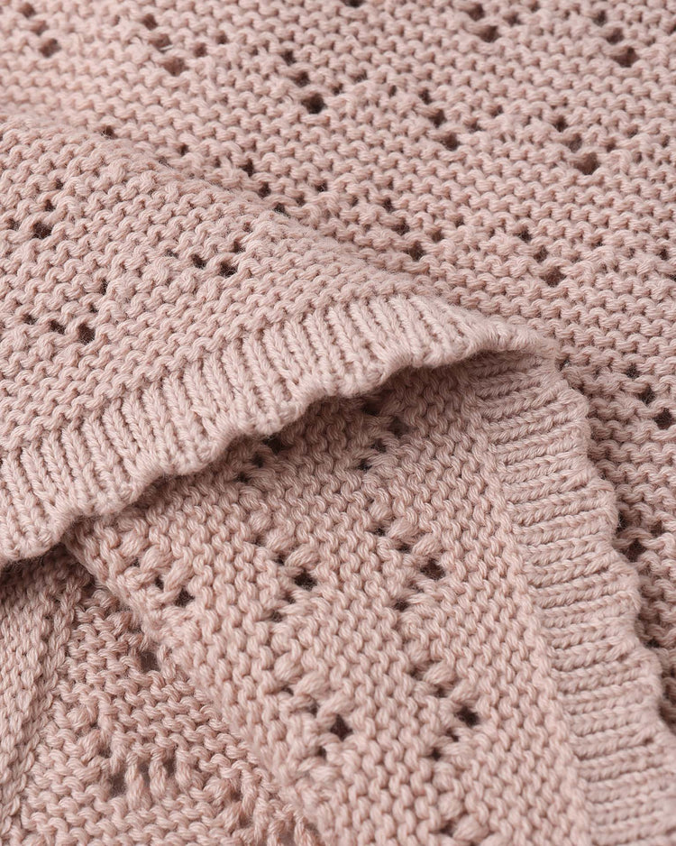 A close-up of quincy mae’s scalloped cardigan in blush, crafted from organic cotton with a delicate diamond eyelet pattern and ribbed edges, highlighting its vintage-inspired texture and intricate knit details.