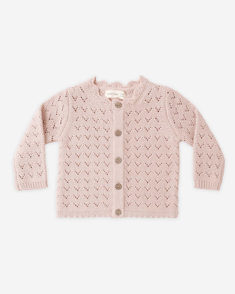 The quincy mae scalloped cardigan in blush is a vintage-inspired, light pink knit with a scalloped neckline, button-down front, eyelet pattern, long sleeves, and a soft, cozy feel for babies.