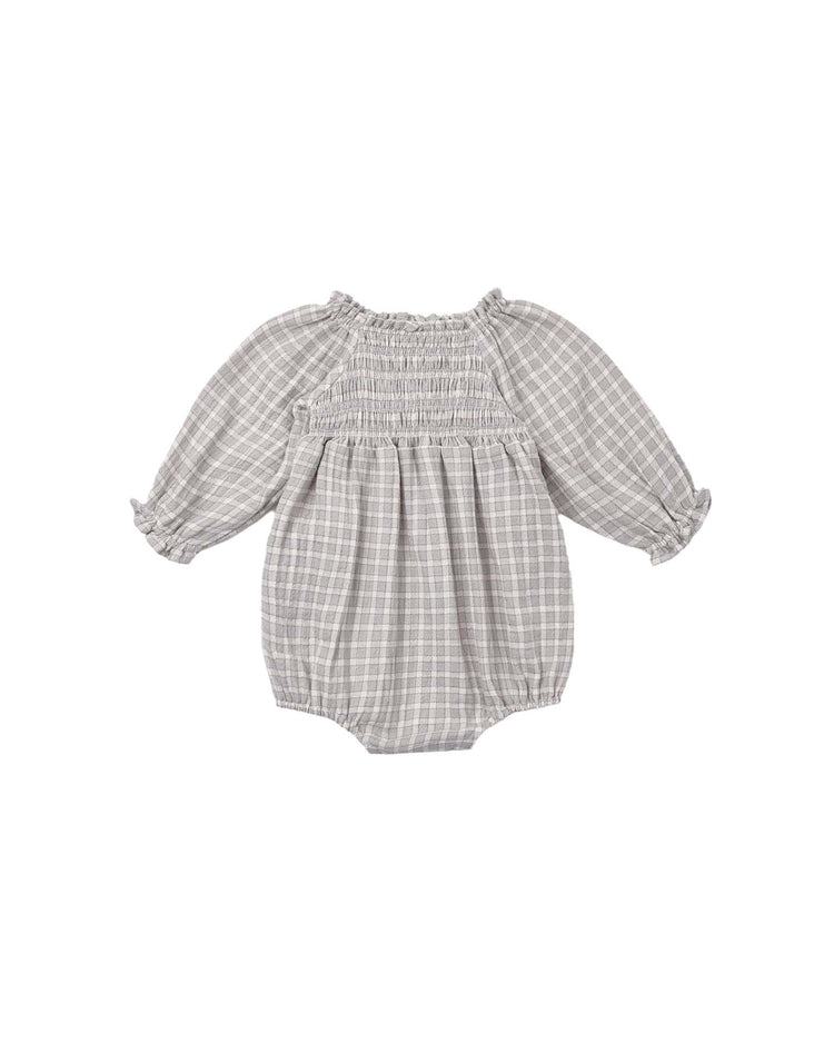 The eden romper in blue gingham by quincy mae features long sleeves, ruffle details at the cuffs, and a smocked bodice. Crafted from soft organic cotton, it is displayed on a white background.