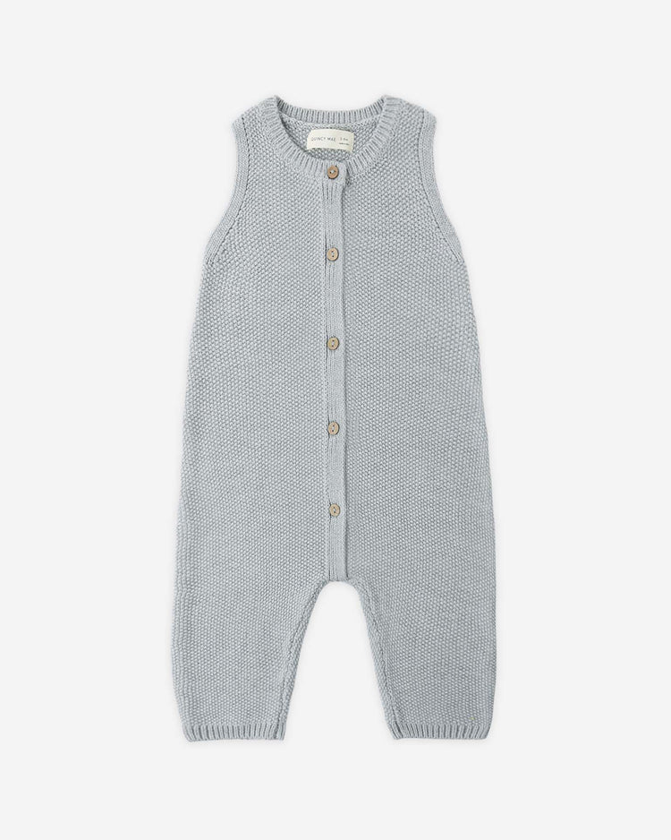 The quincy mae knit jumpsuit in heathered sky is a sleeveless, organic cotton piece with wooden front buttons, round neckline, and long legs—perfect for your baby’s transitional wardrobe. Laid flat on a white background.