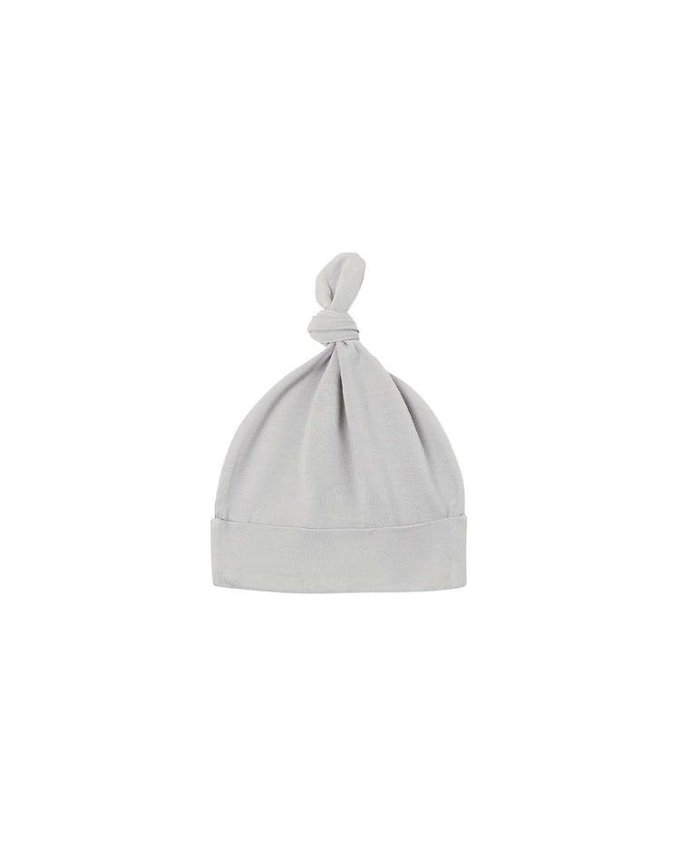 A knotted baby hat in cloud by quincy mae, crafted from organic cotton in light gray, featuring a folded brim and an adorable top knot, displayed against a plain white background.