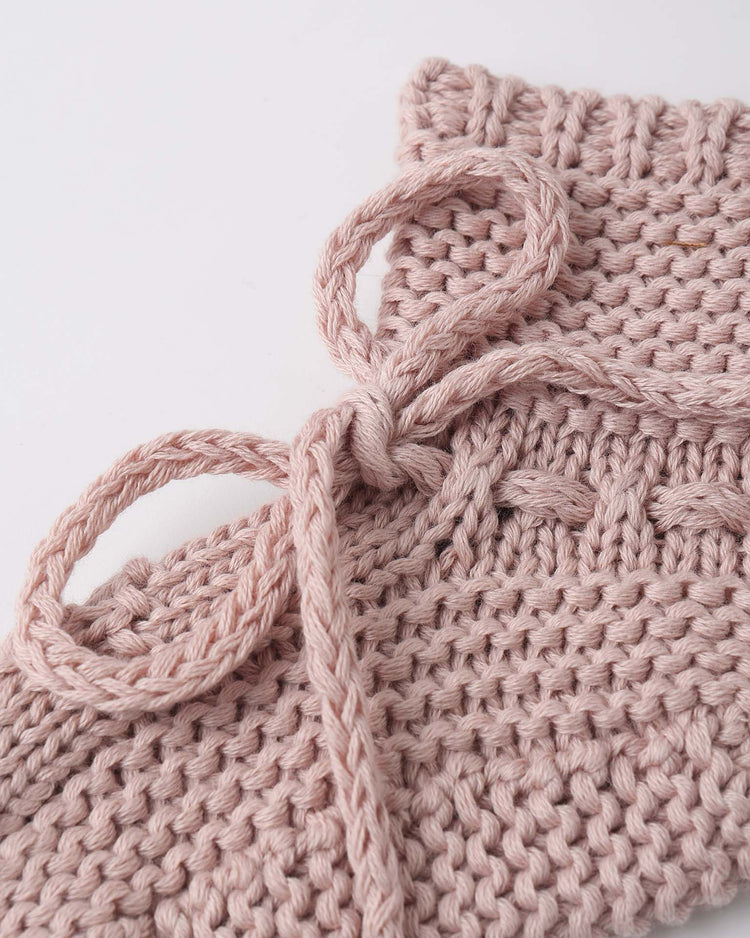Close-up of Quincy Mae’s knit booties in blush, featuring a textured knit pattern and a braided bow—crafted from soft organic cotton.