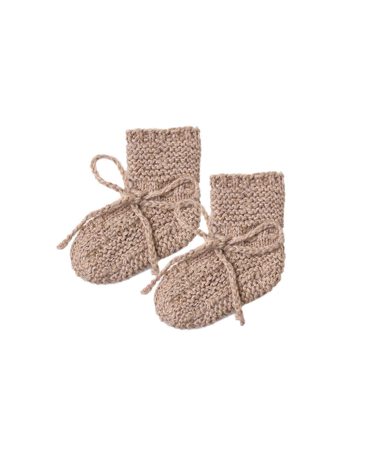 A pair of quincy mae knit booties in heathered almond, made from soft recycled polyester with matching ankle ties, are displayed on a white background.