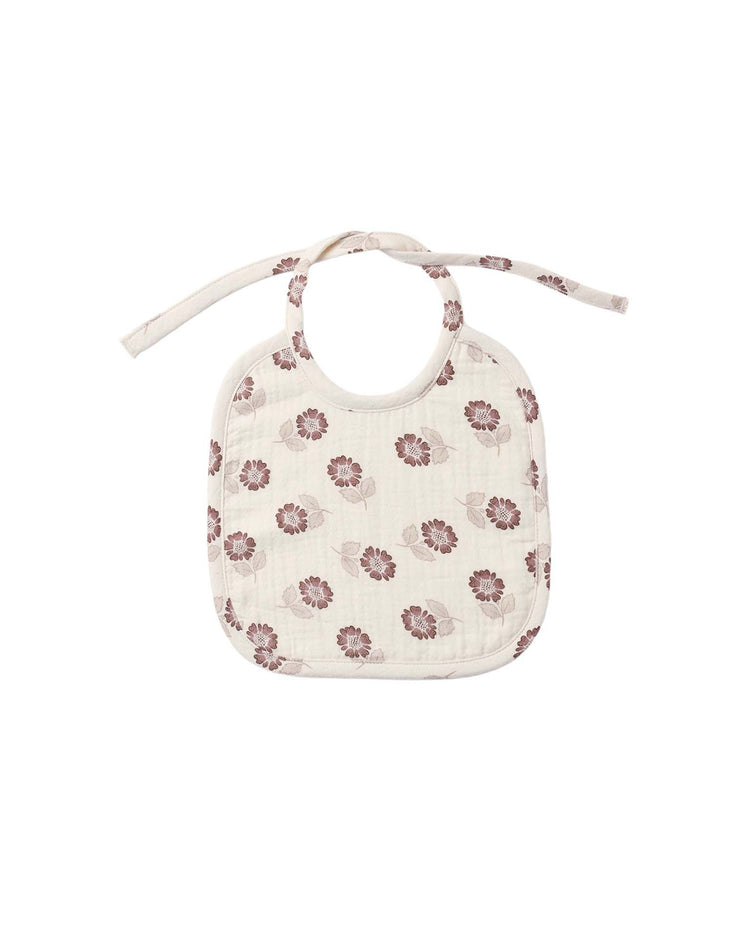 Introducing the woven tie bib in fall floral by quincy mae—a cream-colored organic cotton bib adorned with a quilted floral print of pink flowers and green leaves. This soft, charming accessory features a classic tie closure and is beautifully displayed against a plain white background.