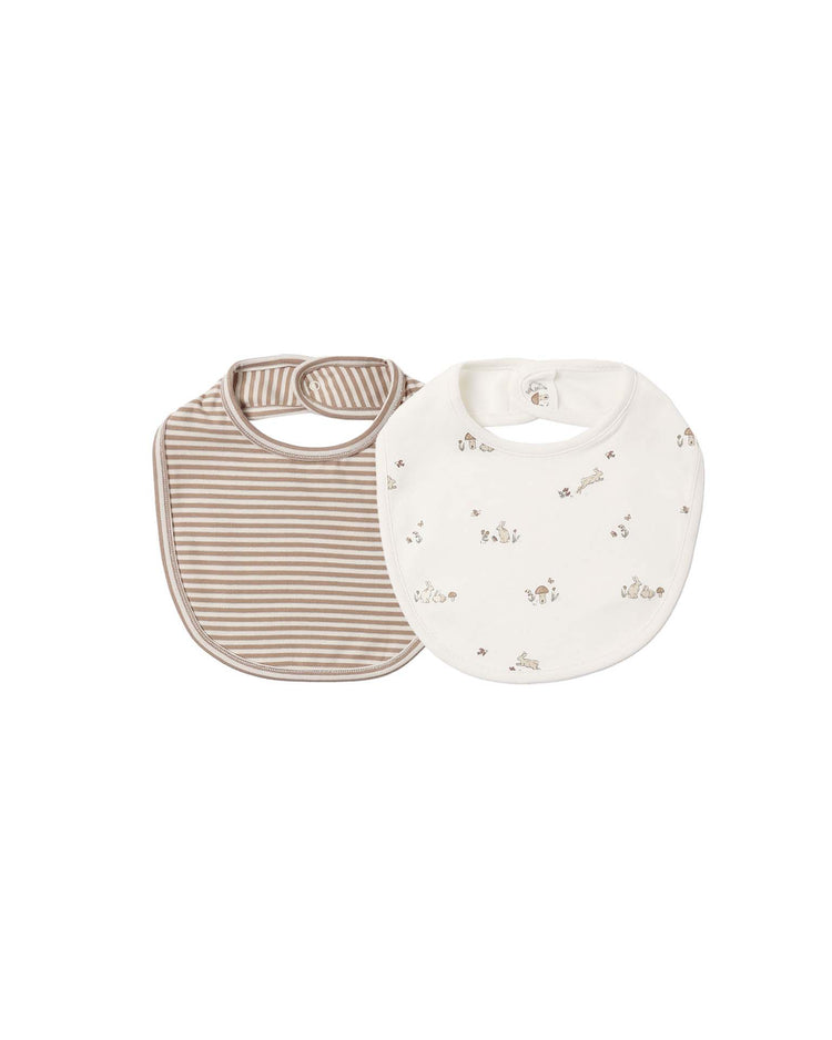 The quincy mae jersey snap bibs bunnies + almond stripe set features two organic cotton bibs: one in a playful bunny print with brown trim, and the other in classic almond and white stripes. Both bibs are crafted from soft jersey fabric and have snap closures at the neck for easy dressing.
