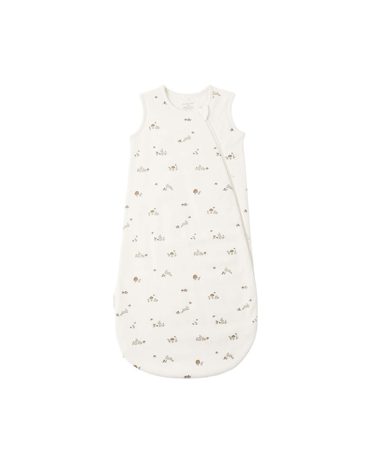 The "jersey sleep bag in bunnies" by Quincy Mae is a white, sleeveless baby sleep sack made from soft organic cotton, featuring a side zipper and a charming small bunny print, displayed on a plain white background.