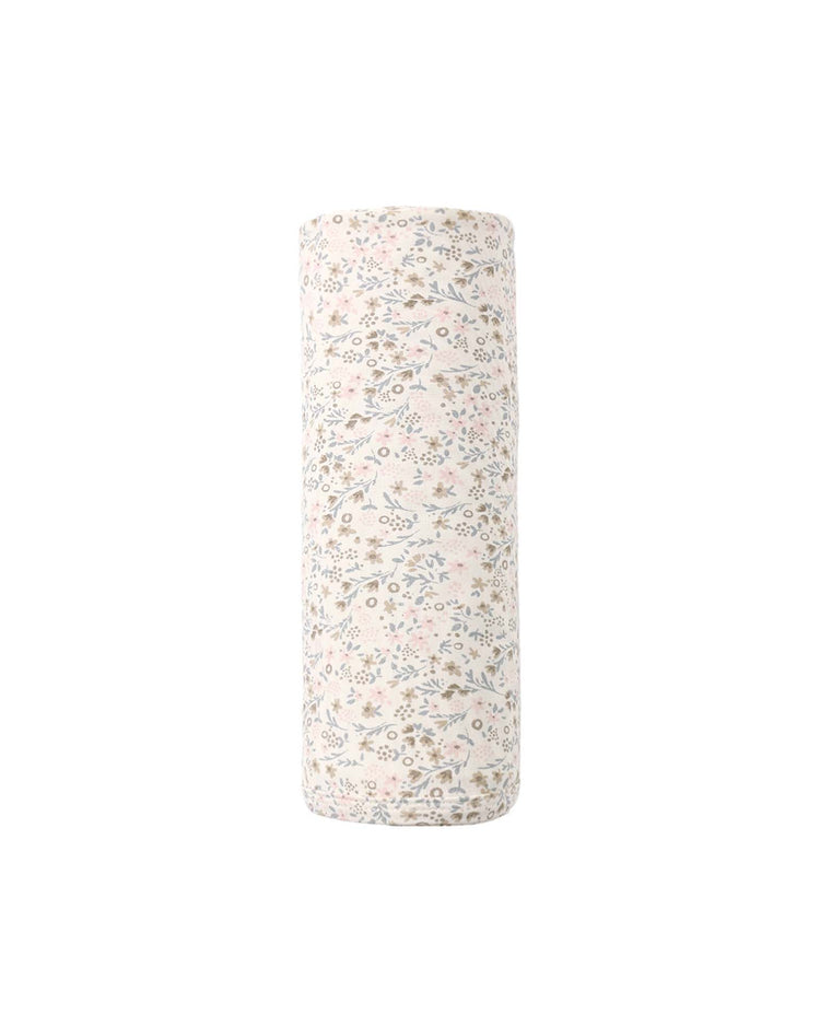 The "bamboo swaddle in bloom" by quincy mae is displayed standing upright against a white background, showcasing its soft bamboo fabric adorned with a light-colored floral print featuring delicate pastel flowers and leaves.