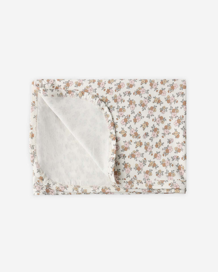 The quincy mae bamboo swaddle in wildflower features a delicate pink, yellow, and green floral print on soft bamboo fabric, shown folded with one corner turned up to display the pattern.