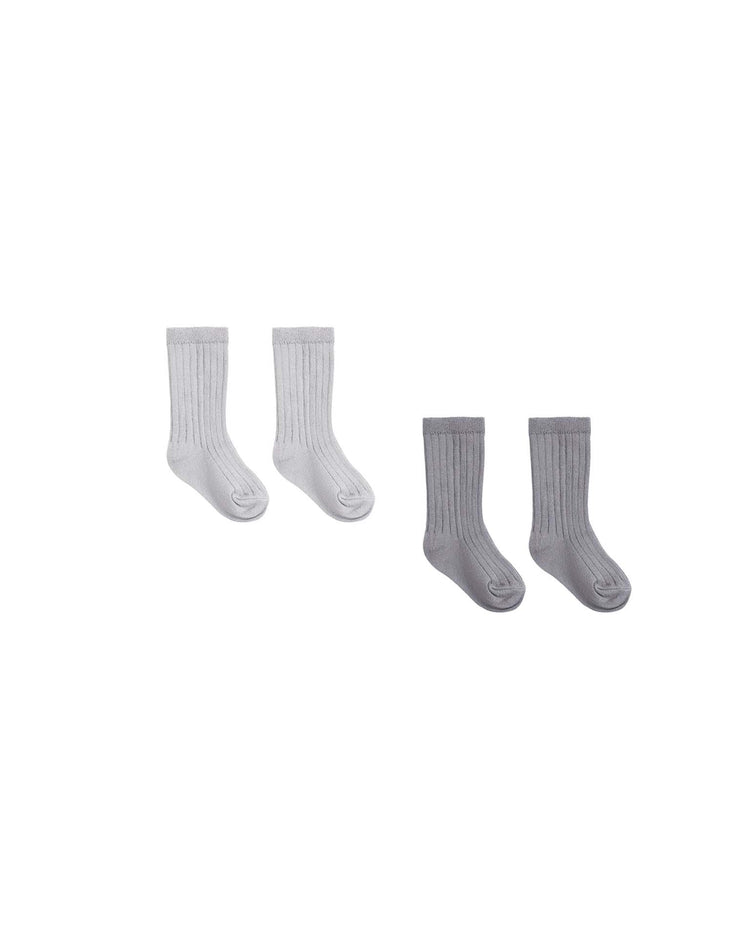 On a white background, two pairs of ribbed baby socks from quincy mae’s socks set in slate + cloud are displayed—one pair in light gray (cloud) and one in dark gray (slate). Made from organic cotton, this boxed set provides cozy comfort and style for little feet.