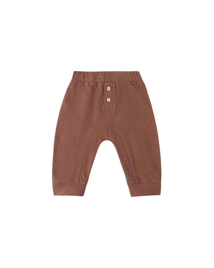 The PREORDER baby cru pant in mulberry by rylee + cru features a relaxed fit, an elastic waistband, two decorative buttons on the front, and cuffed ankles. Crafted from 100% cotton, these brown pull-on pants are displayed on a white background.