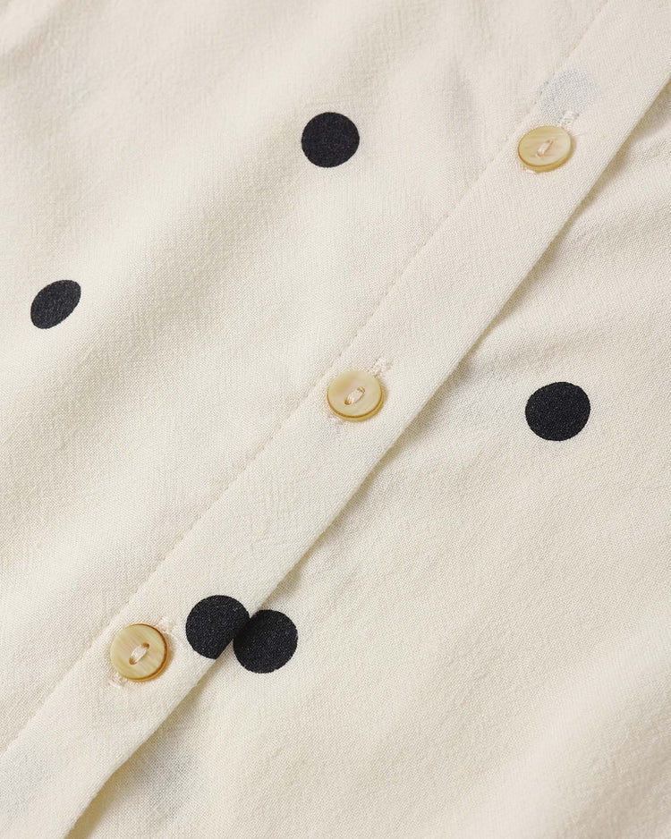 Close-up of the rylee + cru "oceanside top in polka dot," a cream sleeveless cotton blouse with black polka dots and three beige buttons on a vertical seam.