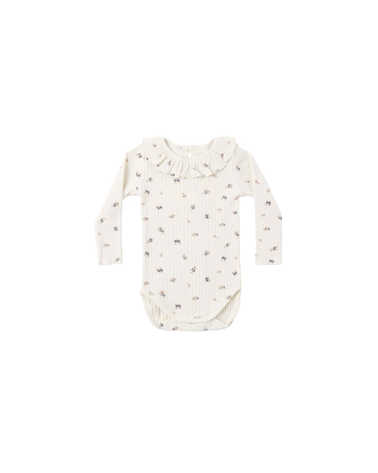 The rylee + cru PREORDER ruffle collar bodysuit in natural ditsy is a cream-colored, long-sleeve knit bodysuit featuring a charming ruffle collar and an all-over natural ditsy print. The garment is shown laid flat on a white background.