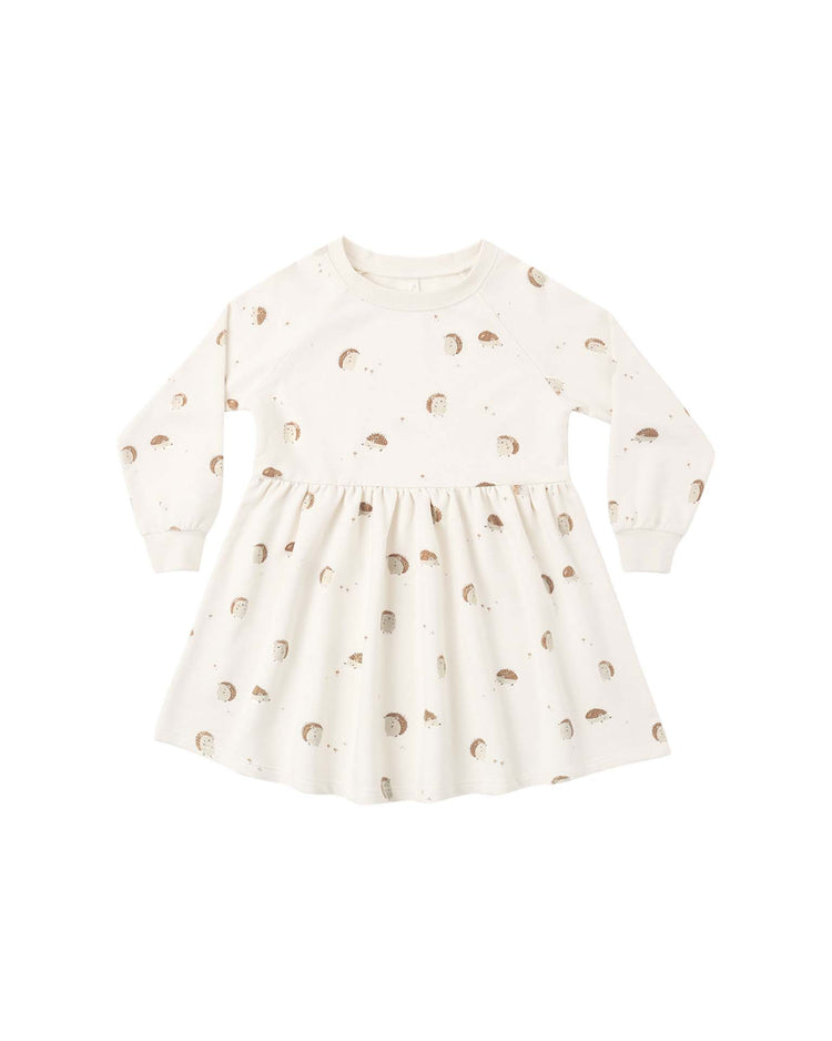 The PREORDER raglan dress in hedgehog by rylee + cru is a cream-colored, long-sleeve mini dress for toddlers. It features a flared skirt, ribbed cuffs and collar, and an all-over playful hedgehog print—perfect for young children.
