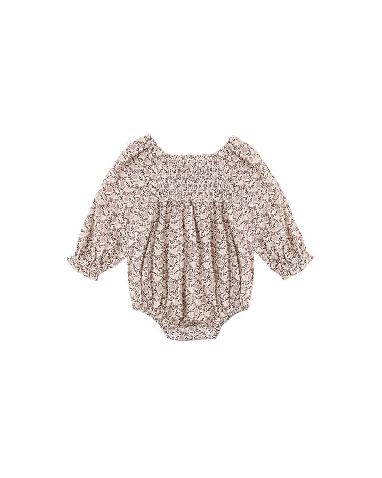 The rylee + cru Adelaide Romper in Primrose for babies, made from 100% cotton with a lovely floral print, showcases smocked detailing at the elastic neckline and ruffled cuffs, shown on a white background.