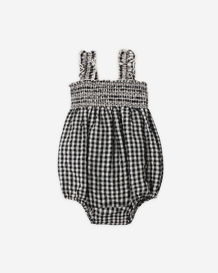The julia romper in black check by rylee + cru features ruffled shoulder straps, a smocked bodice, and elastic leg openings. This charming romper is made from a soft cotton-polyester blend and shown on a white background.