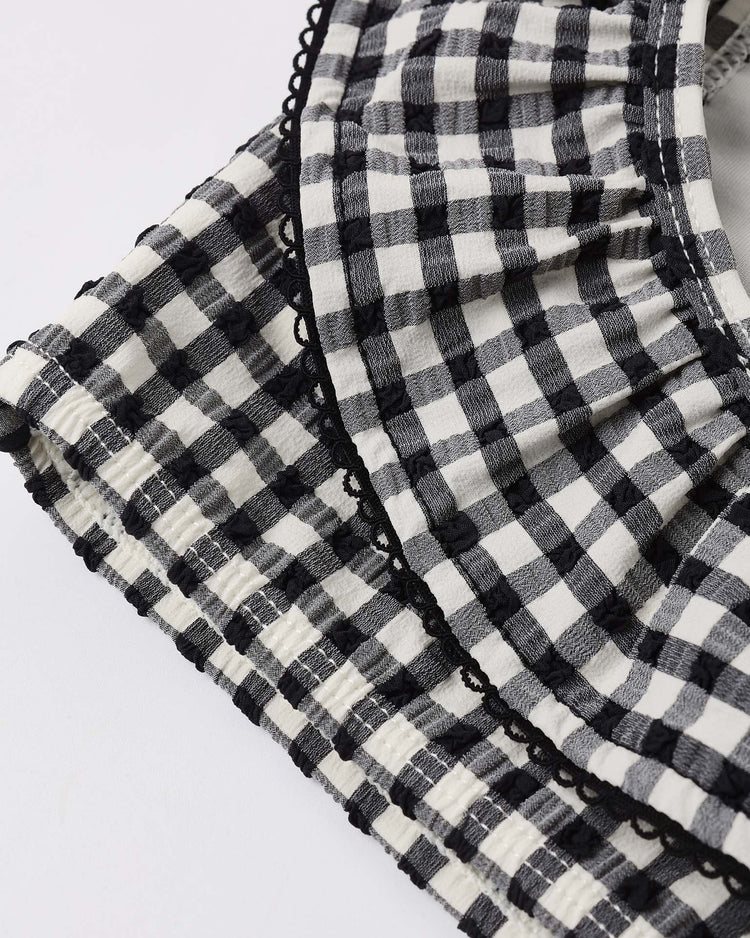 Close-up of the margot bikini in black gingham by rylee + cru, featuring alternating black and white squares, ruffled detailing, and a scalloped black trim along the edge.