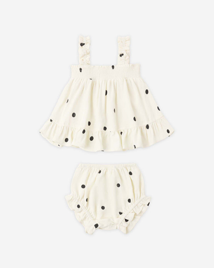The lala set in polka dot by rylee + cru features a white sleeveless top with black polka dots and ruffle details, paired with matching flutter bloomers—both finished with charming gathered accents.