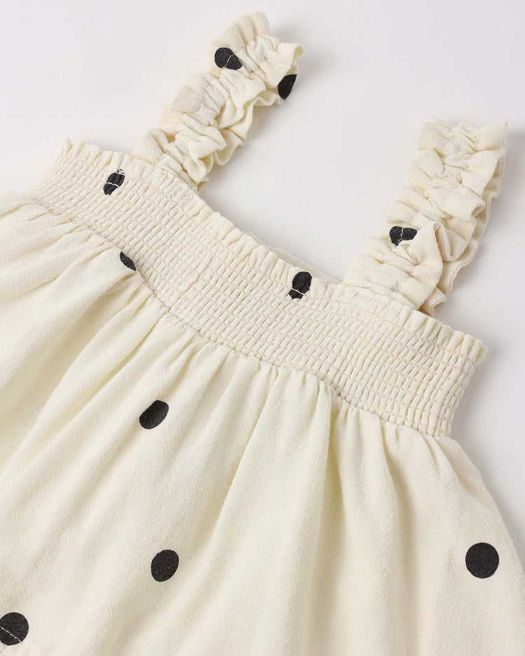 A close-up of the lala set in polka dot by rylee + cru, featuring a cream dress with black polka dots, gathered ruffle shoulder straps, a smocked elastic top, and textured fabric—perfectly paired with flutter bloomers for a playful look.