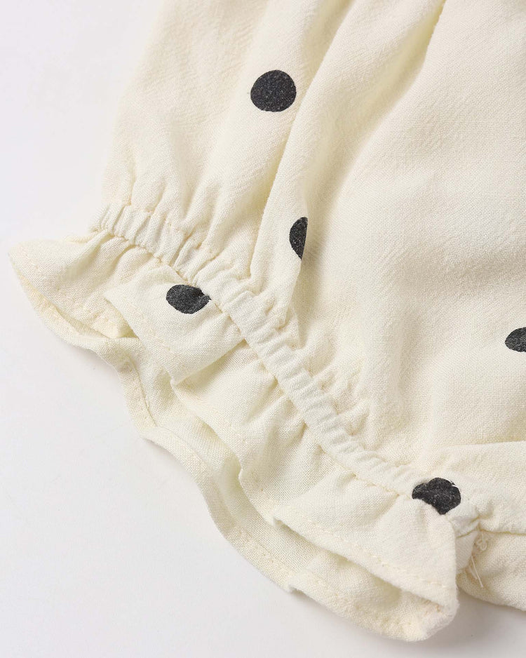 Close-up of the lala set in polka dot by rylee + cru, showing cream-colored fabric with black polka dots and elasticated ruffle edging, likely part of a sleeve or flutter bloomers.