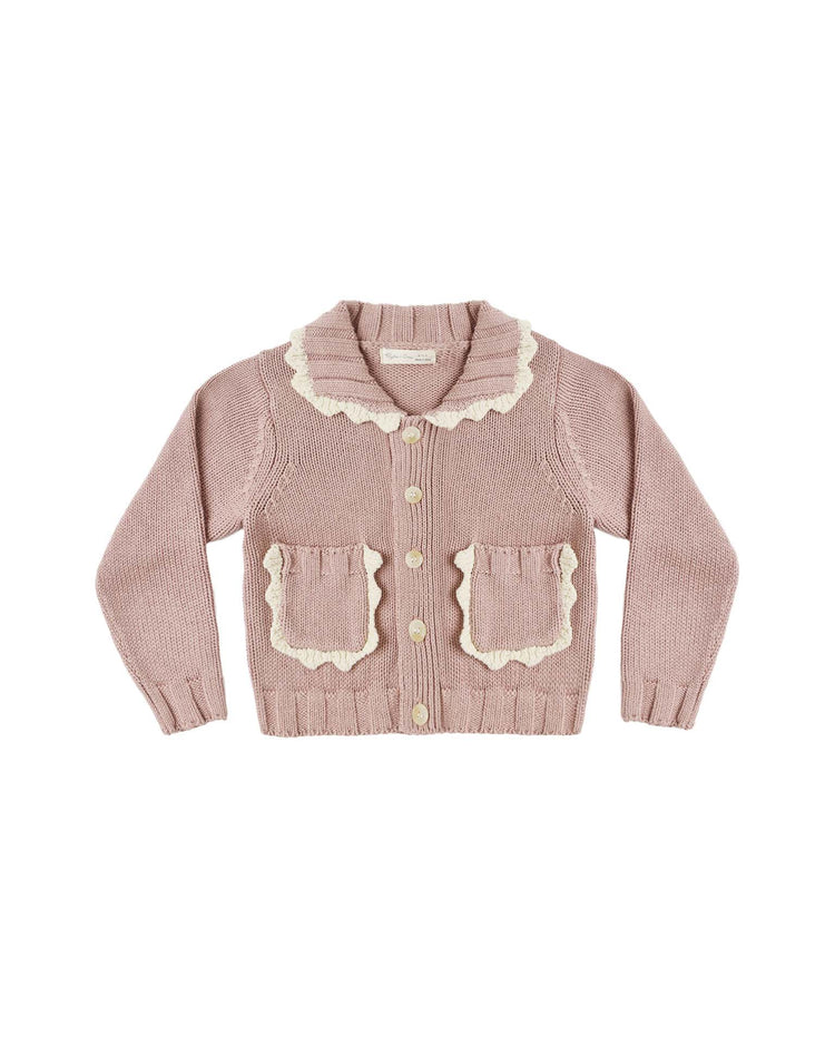 The “collared cardigan in rosewood” by rylee + cru is a light pink 100% cotton cardigan, featuring a collared neckline with cream crochet scallop detailing along the ruffled trim and two front pockets. It has a button-down front and is shown laid flat on a white background.