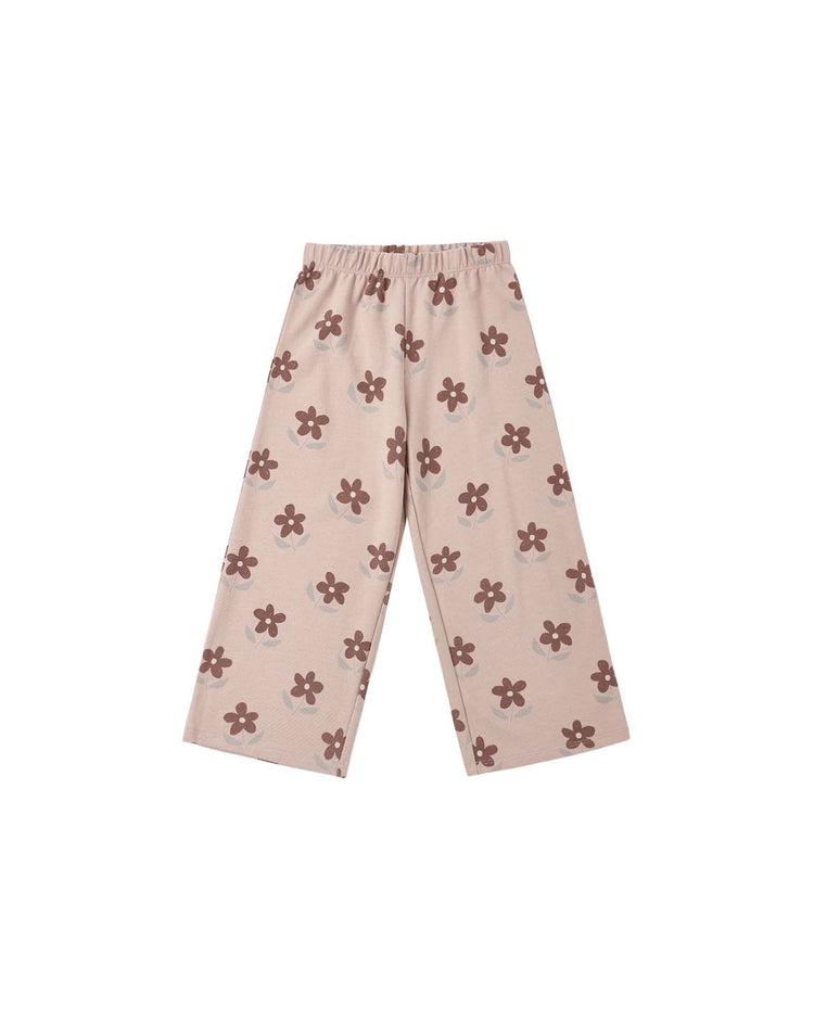 The PREORDER track pant in daisy by rylee + cru features a beige wide-leg silhouette with a rosewood and brown daisy print, an elastic waistband, and no visible pockets, shown laid flat on a white background.