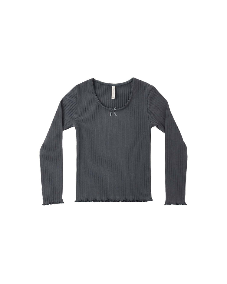 The rylee + cru ribbed long sleeve in midnight is displayed flat on a white background, showcasing its scoop neckline adorned with a delicate center bow and gently ruffled edges at the cuffs and hem.