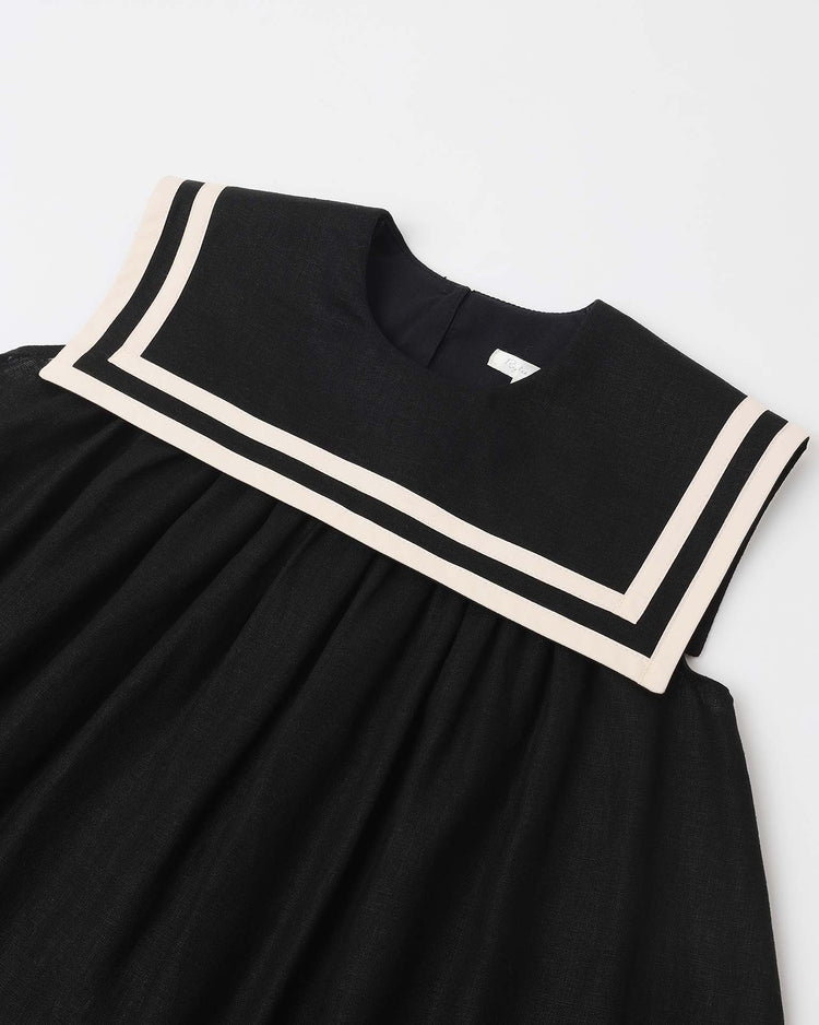 The rylee + cru sailor dress in black features a vintage-inspired wide square collar with two white stripes, shown on a flat white surface.