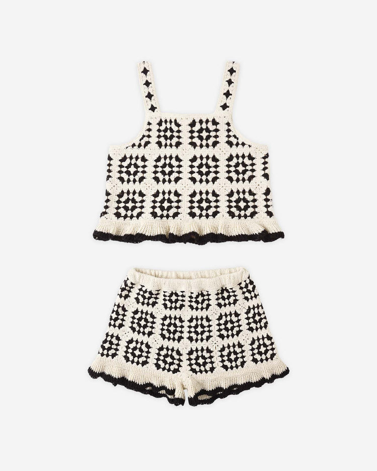 The kira set in abstract by rylee + cru features a black and white crochet knit summer set with a sleeveless top and cotton shorts, checkered pattern, and ruffled edges, displayed on a white background.