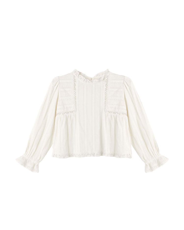 The cecile blouse in natural by rylee + cru is a long-sleeved white top crafted from 100% cotton, featuring delicate lace trim, pintuck details on the chest, ruffled cuffs, and a high neckline for a timeless Prairie-inspired silhouette. Displayed against a plain white background.