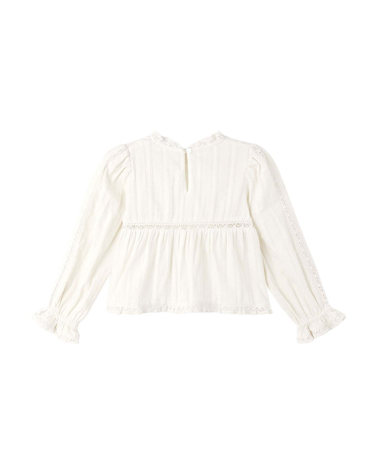 The cecile blouse in natural by rylee + cru is a long-sleeve, 100% cotton Prairie blouse featuring a pleated texture, delicate lace trim on the sleeves, hem, and neckline, and a keyhole button closure at the back.