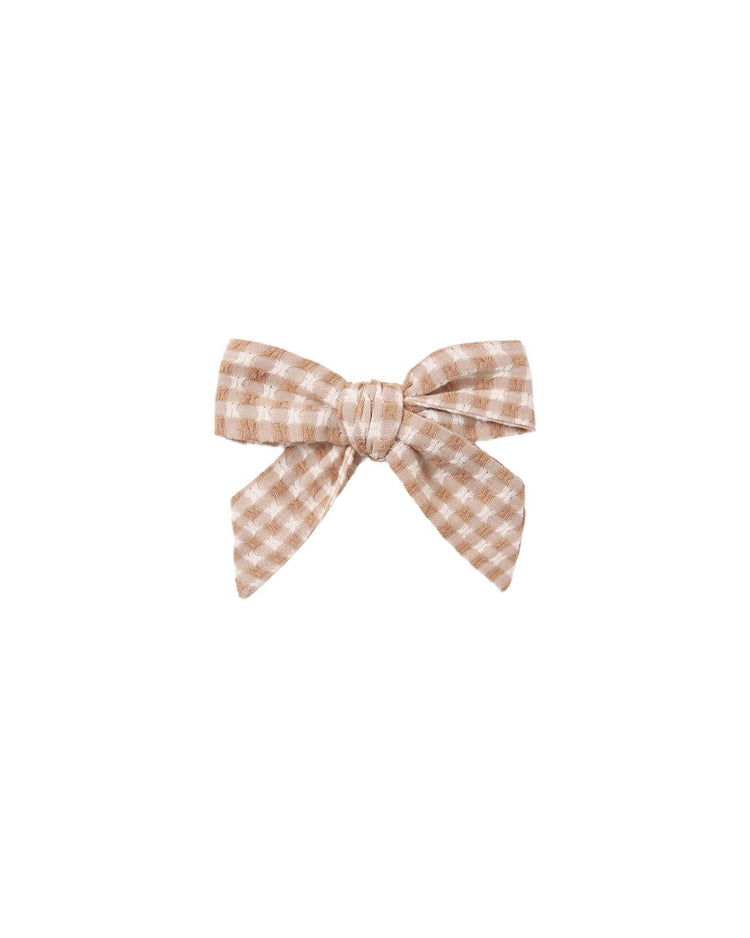 The rylee + cru “bow in fawn gingham” features a charming beige and white checkered cotton design with two loose ends, shown against a plain white background.